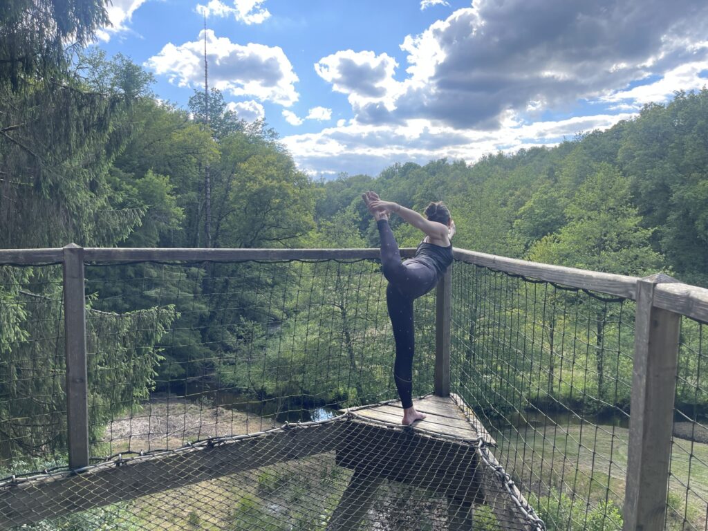 Debout sur une jambe, la posture de yoga du danseur est exécutée en hauteur avec vue imprenable sur la fôret