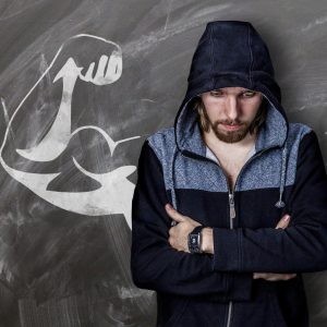 Un homme replié sur lui et en manque de confiance, alors que derrière lui sont dessinés les bras musclés de popeye